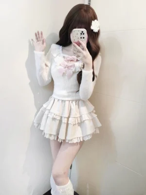 Jirai Kei white sweater and tiered ruffle skirt set full body front view with pearl bow ornament, worn with white leg warmers and white flower hairpin, soft fuzzy knit texture and off-shoulder neckline visible