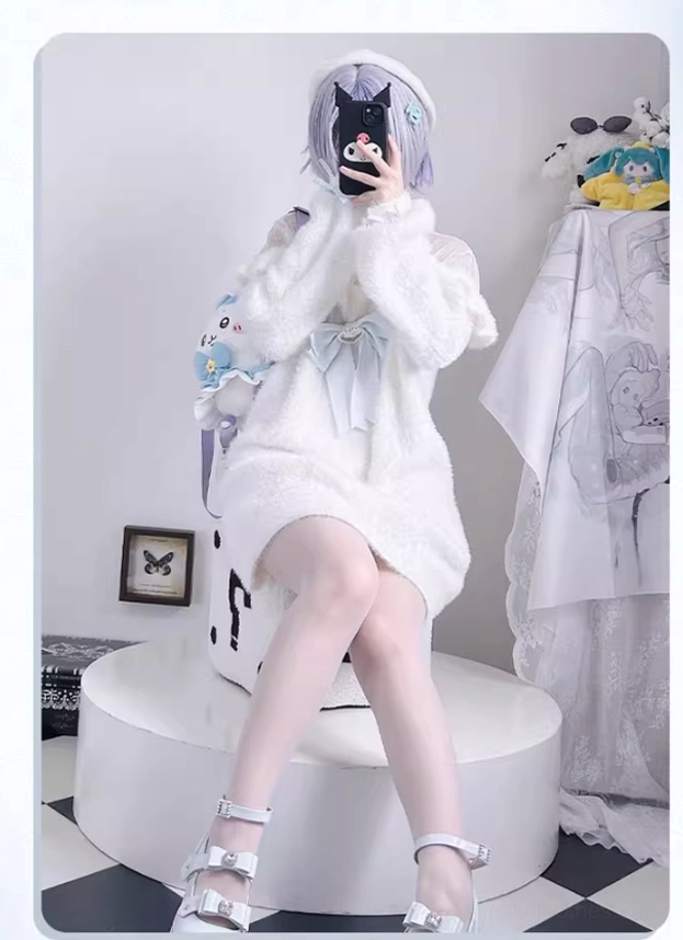 Full-body sitting view of white off-shoulder fuzzy sweater dress with light blue front bow accent on checkered studio floor
