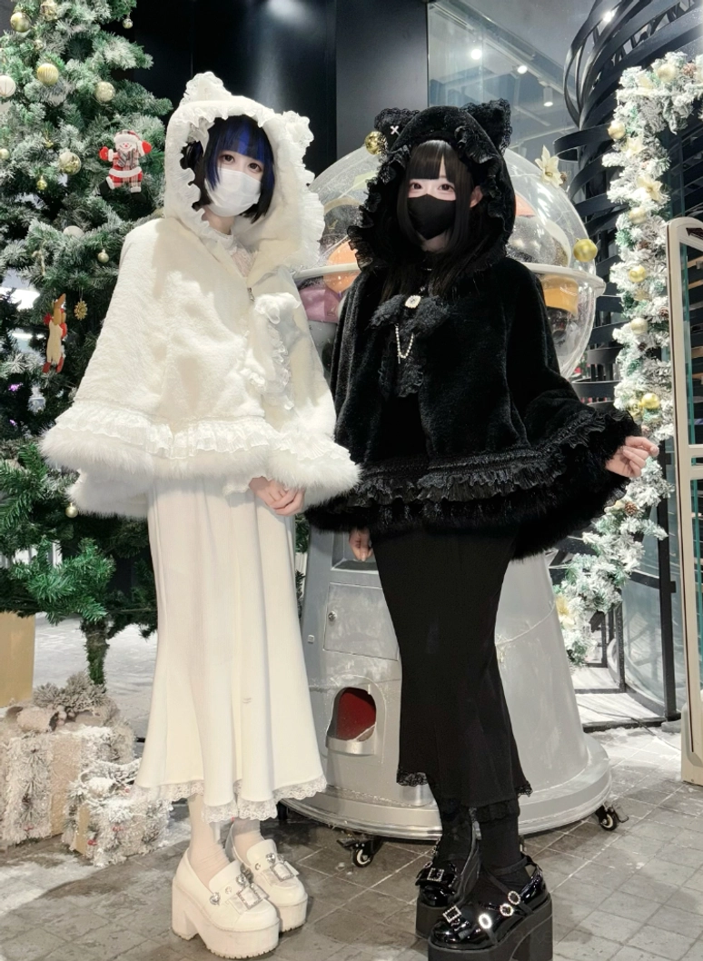 Three-quarter front view of models in black and white jirai kei fleece cape hoodies styled with platform Mary Jane shoes and matching aesthetics