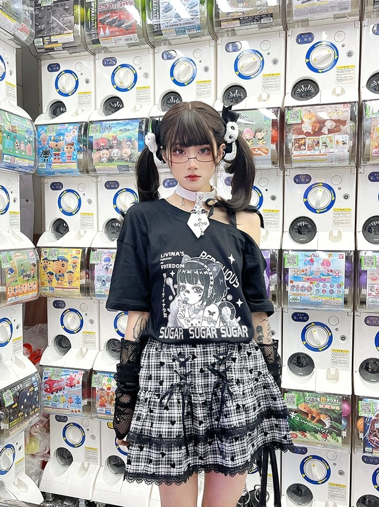 Squatting pose Y2K anime print outfit featuring black cold-shoulder tee paired with plaid ruffle skirt, styled with fingerless gloves and twin-tail hair clips in game center