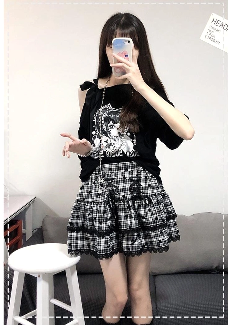 Full-body Y2K Jirai Kei two-piece skirt set featuring black off-shoulder anime graphic tee with cold-shoulder strap and black-white plaid ruffle mini skirt with lace trim, worn as complete outfit