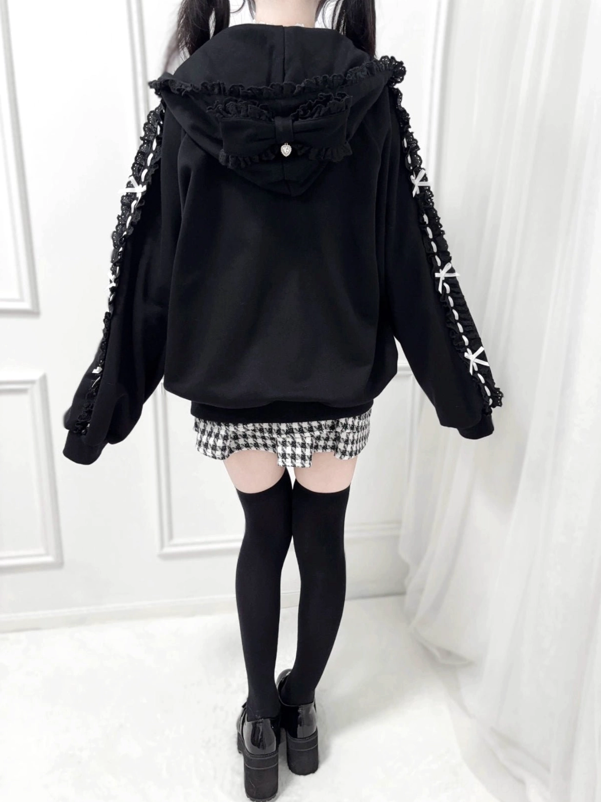 Back view of black Jirai Kei zip-up hoodie, showcasing ruffled hood construction with pearl details and ribbon sleeve trim embellishments