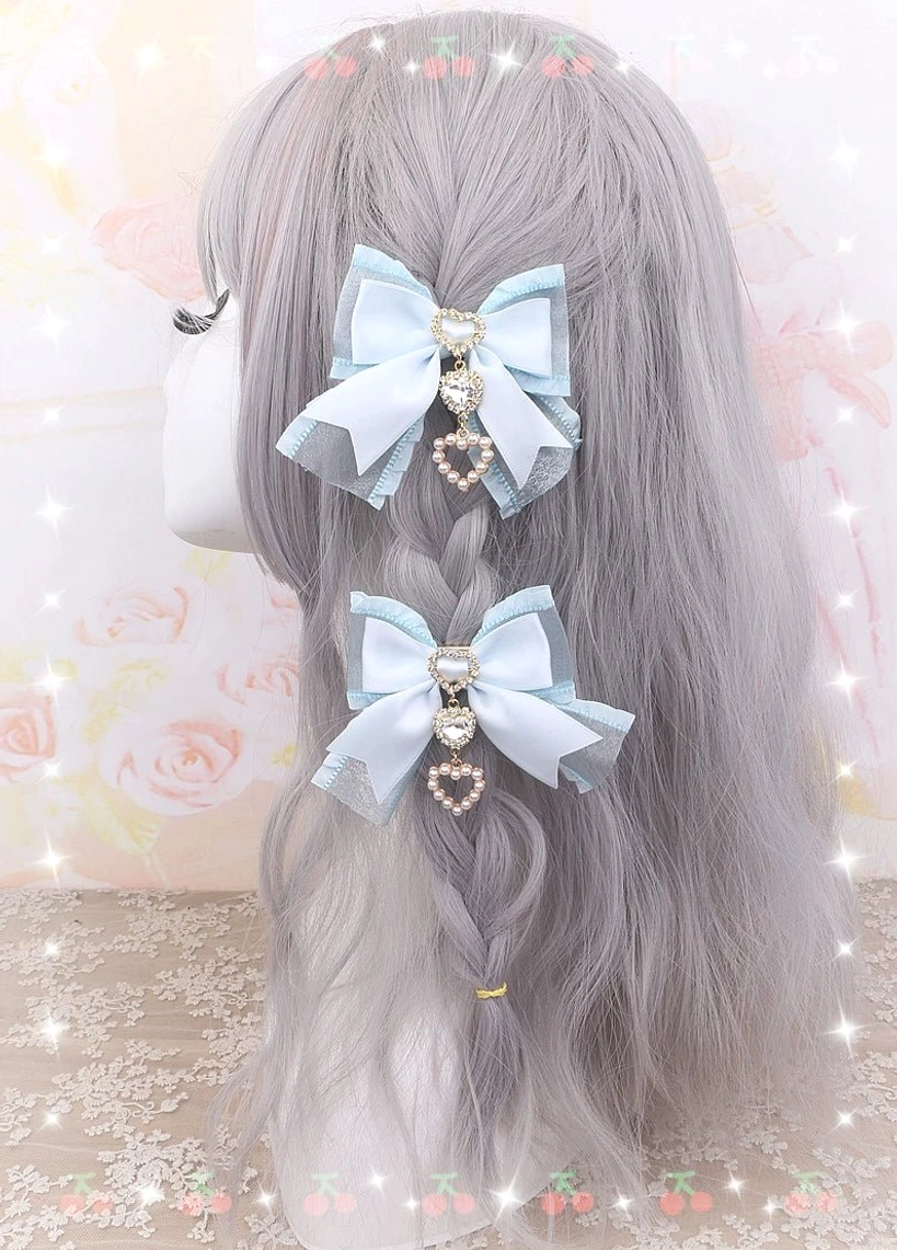 Layered dusty pink bow hair clips with heart rhinestone pendants shown on blonde braided wig mannequin - back profile