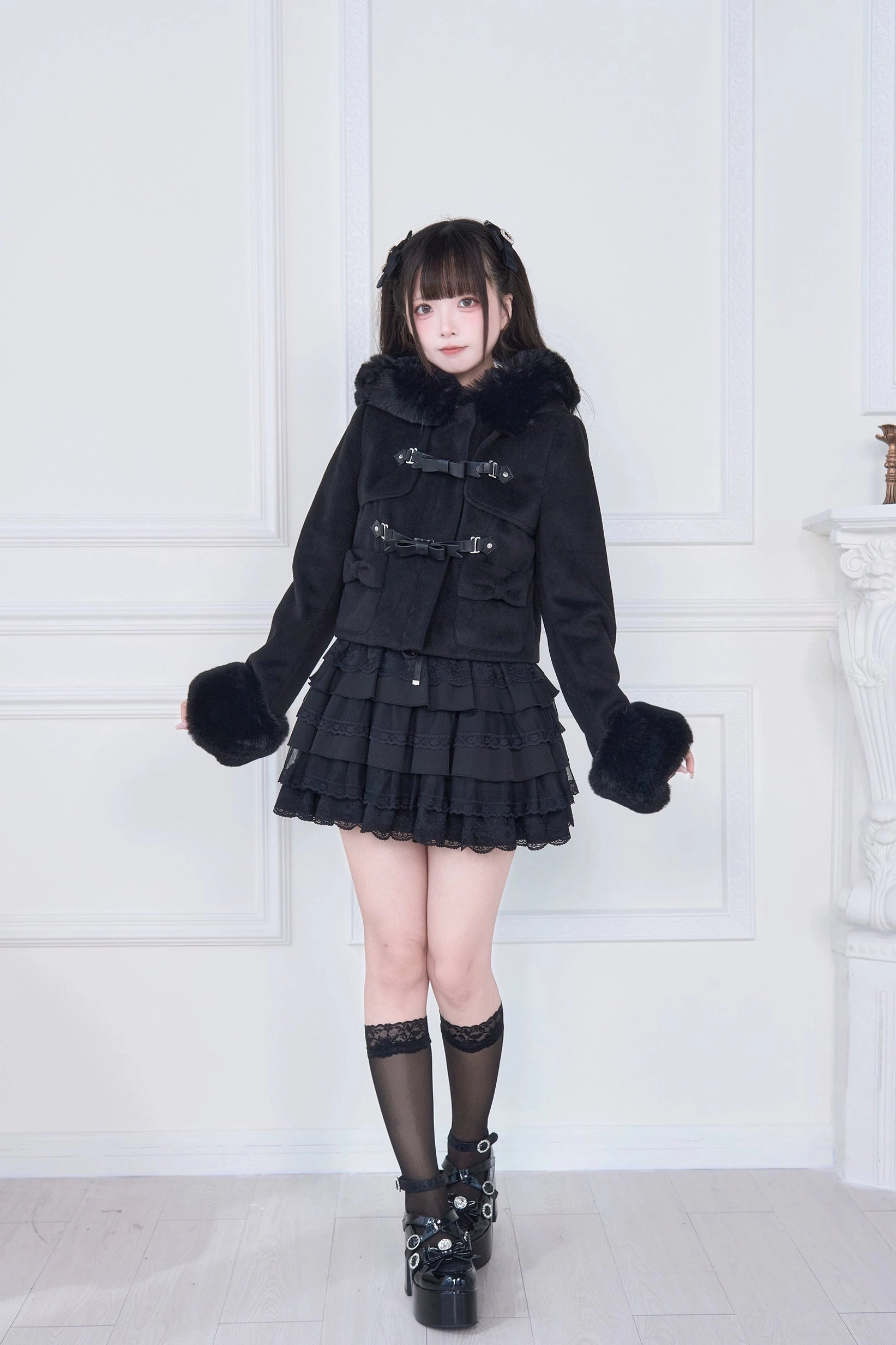 Light apricot hooded rousangata coat flat lay product photography, showing beige coat silhouette, fluffy white fur cuffs, and decorative bow accents