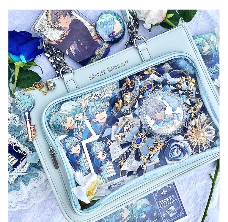 Light blue checkered ita bag overhead view with complex anime badges and charm decorations and clear window