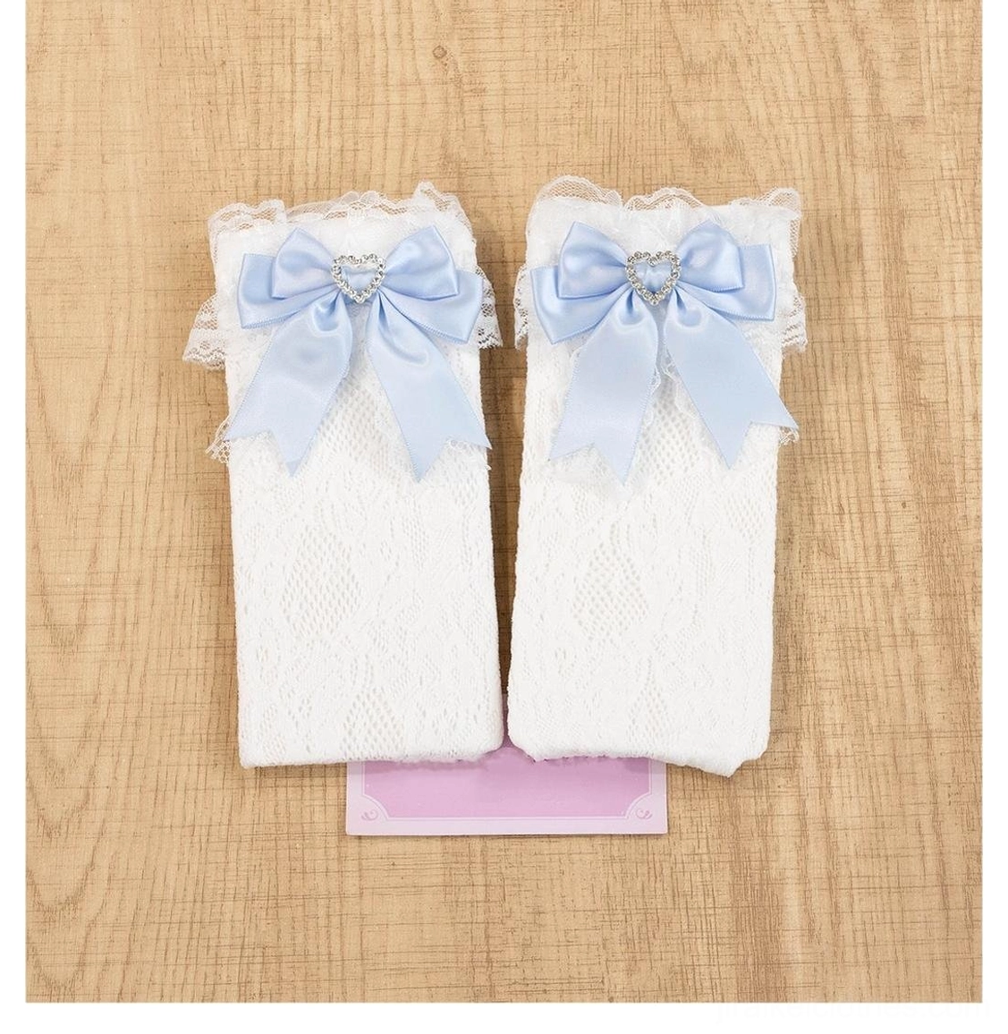 Light blue jirai kei lace socks with heart-shaped rhinestones and decorative satin bows in soft pastel tone