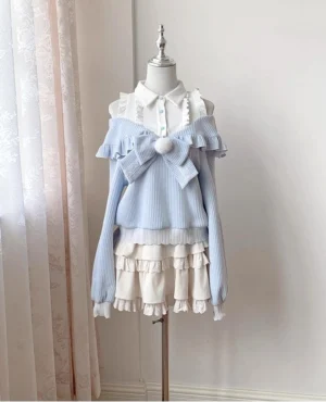 Light blue off-shoulder Tenshi Kaiwai sweater with detachable pom-pom bow and tiered ruffle skirt set displayed on studio background flat lay view