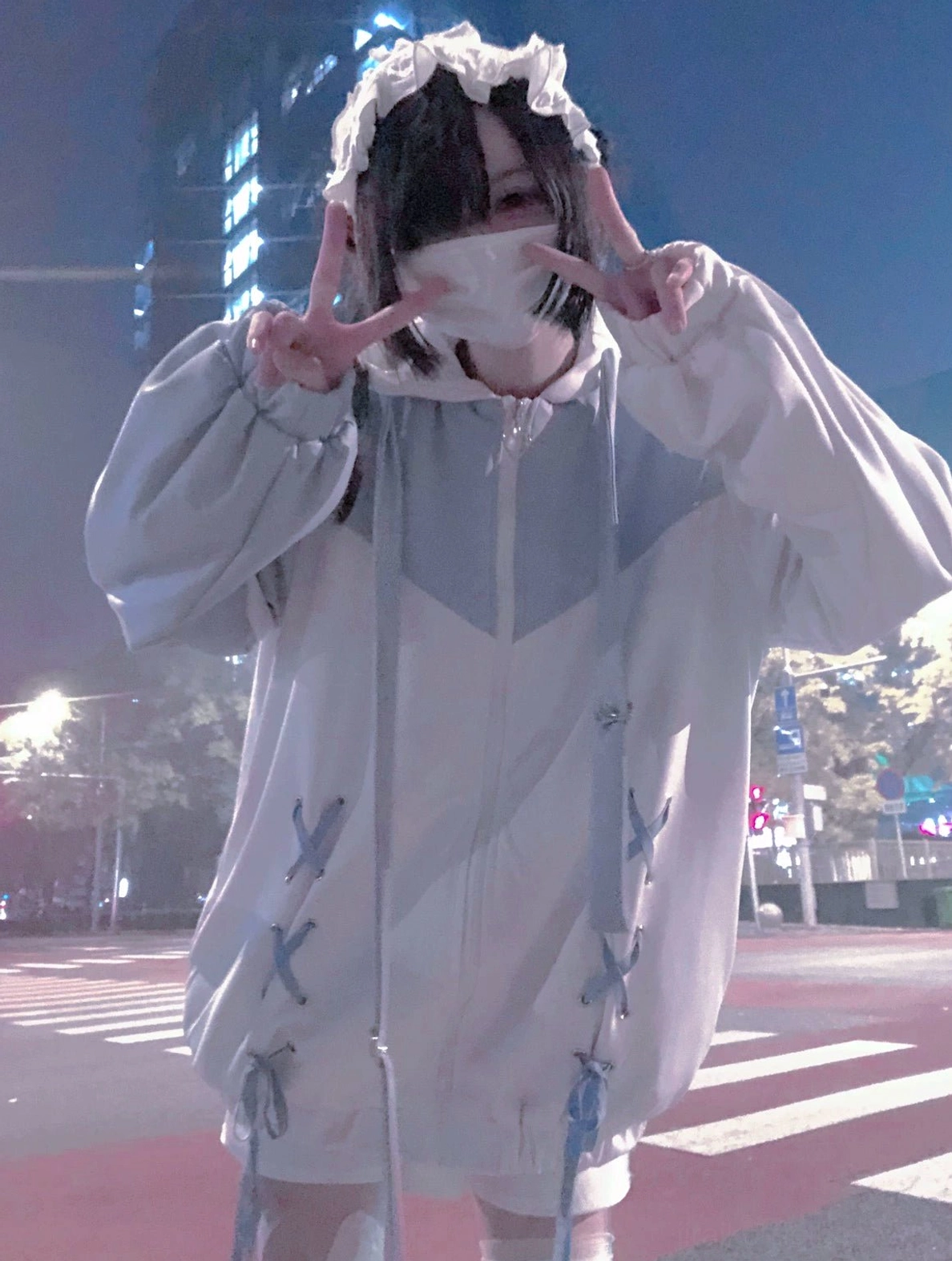 Light blue-white Tenshi Kaiwai lace-up hooded jacket worn outdoors at zebra crossing at night with maid hairband and cross-lacing details visible