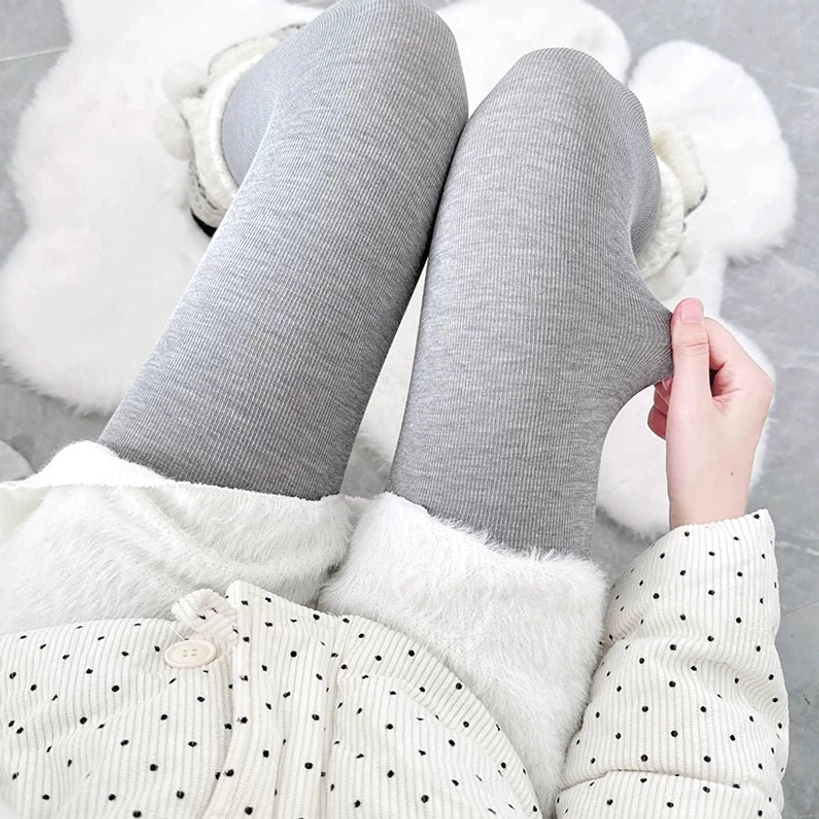 Light gray vertical ribbed footed tights worn with polka dot pajamas, hand adjusting the tights, top-down close-up showing heather gray color and fine ribbed fabric texture for spring-summer Jirai layering