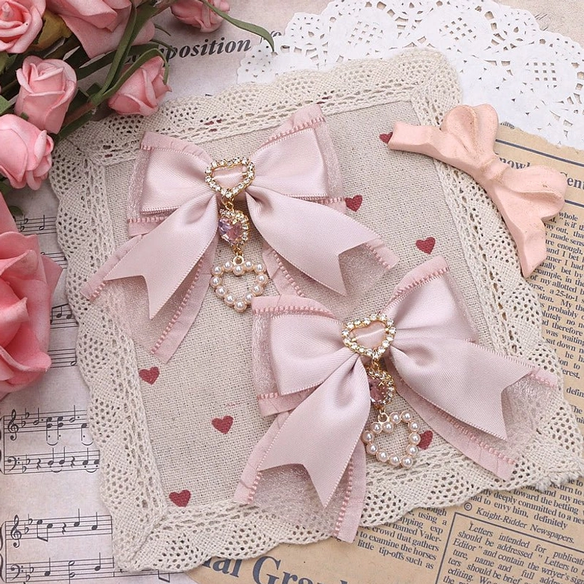 Light pink simple bow hair clips with small heart rhinestone pendants on blonde braided wig - back profile view