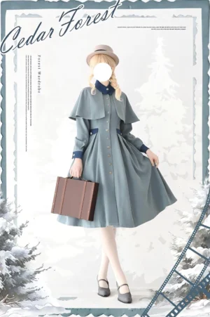 Classic Lolita coat dress in dusty grey-blue with detachable cape, worn by blonde model in winter forest setting, showcasing front silhouette and removable shoulder capelet