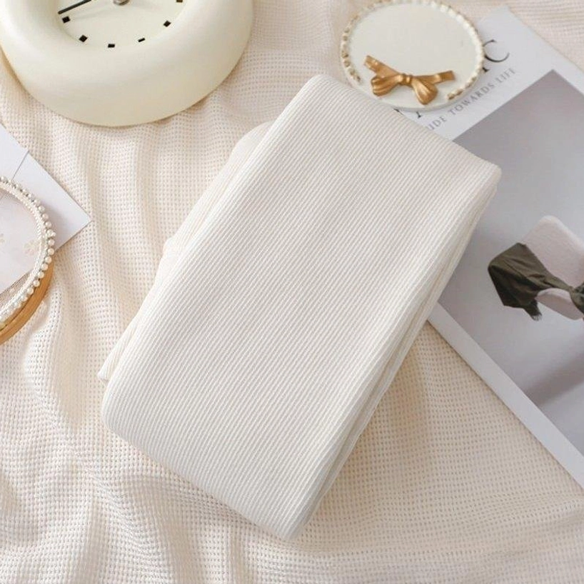 Milky white ribbed solid footed tights folded neatly on cozy home decor background, flat lay product photography showing fine vertical ribbed texture and soft creamy white colorway perfect for Jirai outfits