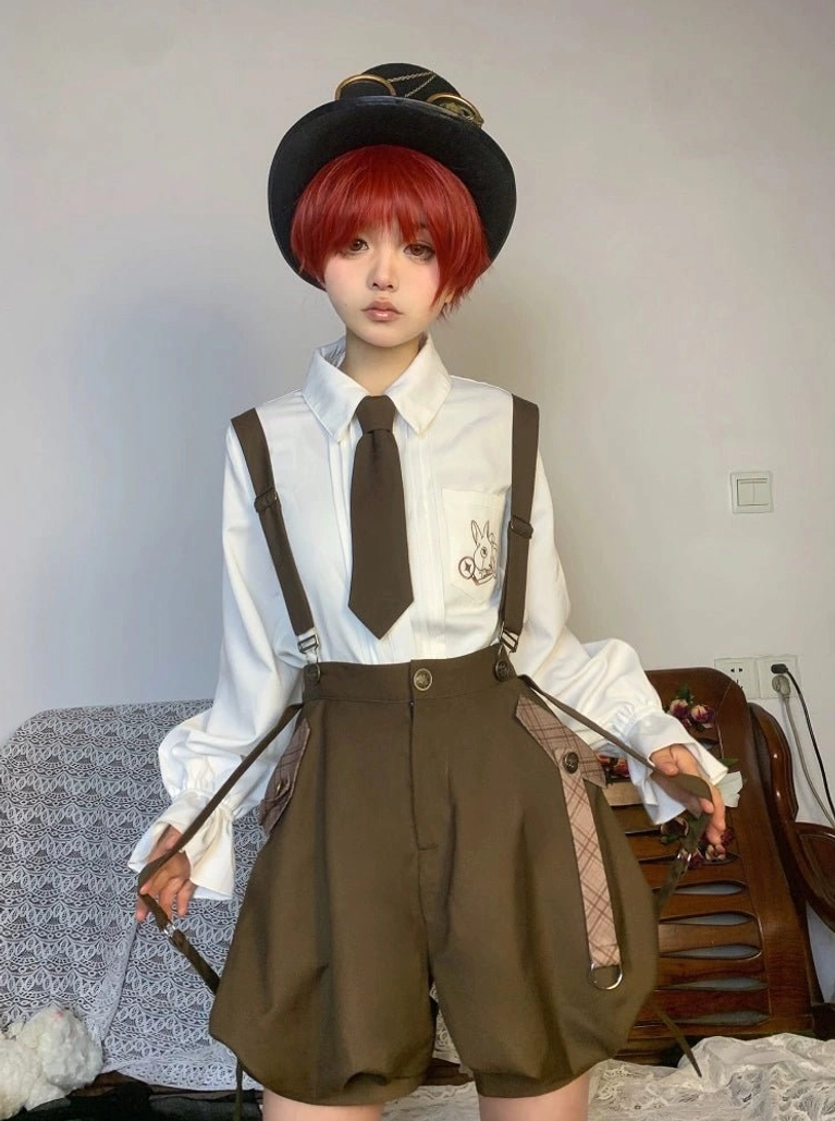 Ouji Lolita shirt and suspender shorts ensemble on red-haired model in top hat and formal necktie, featuring chest embroidery detail, argyle suspender straps, and indoor formal interior setting
