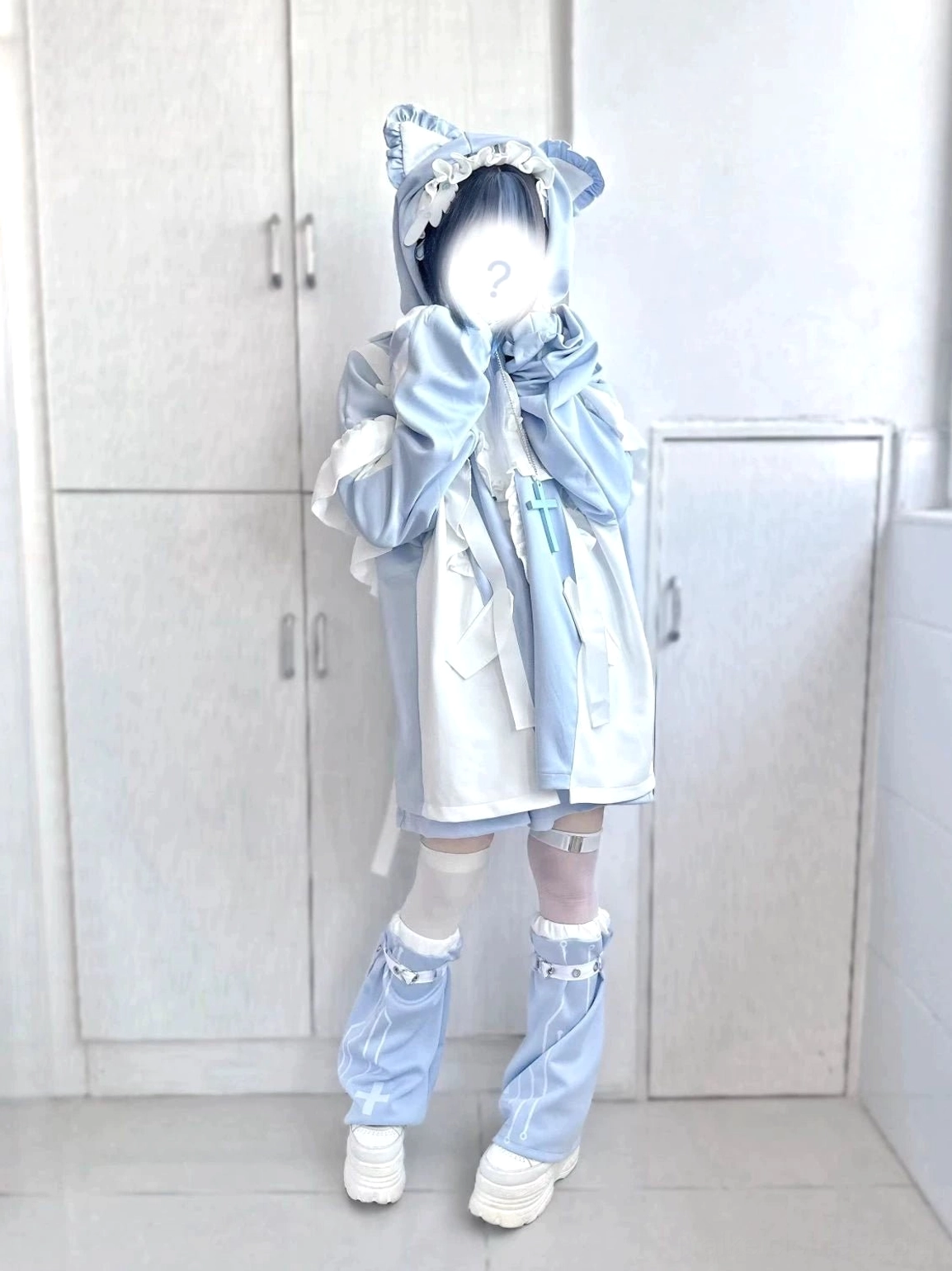 Loose-fitting pastel blue tenshi coat with cat ear hood and flounced chest detail, paired with light blue leg warmers and white platform shoes in mirror reflection