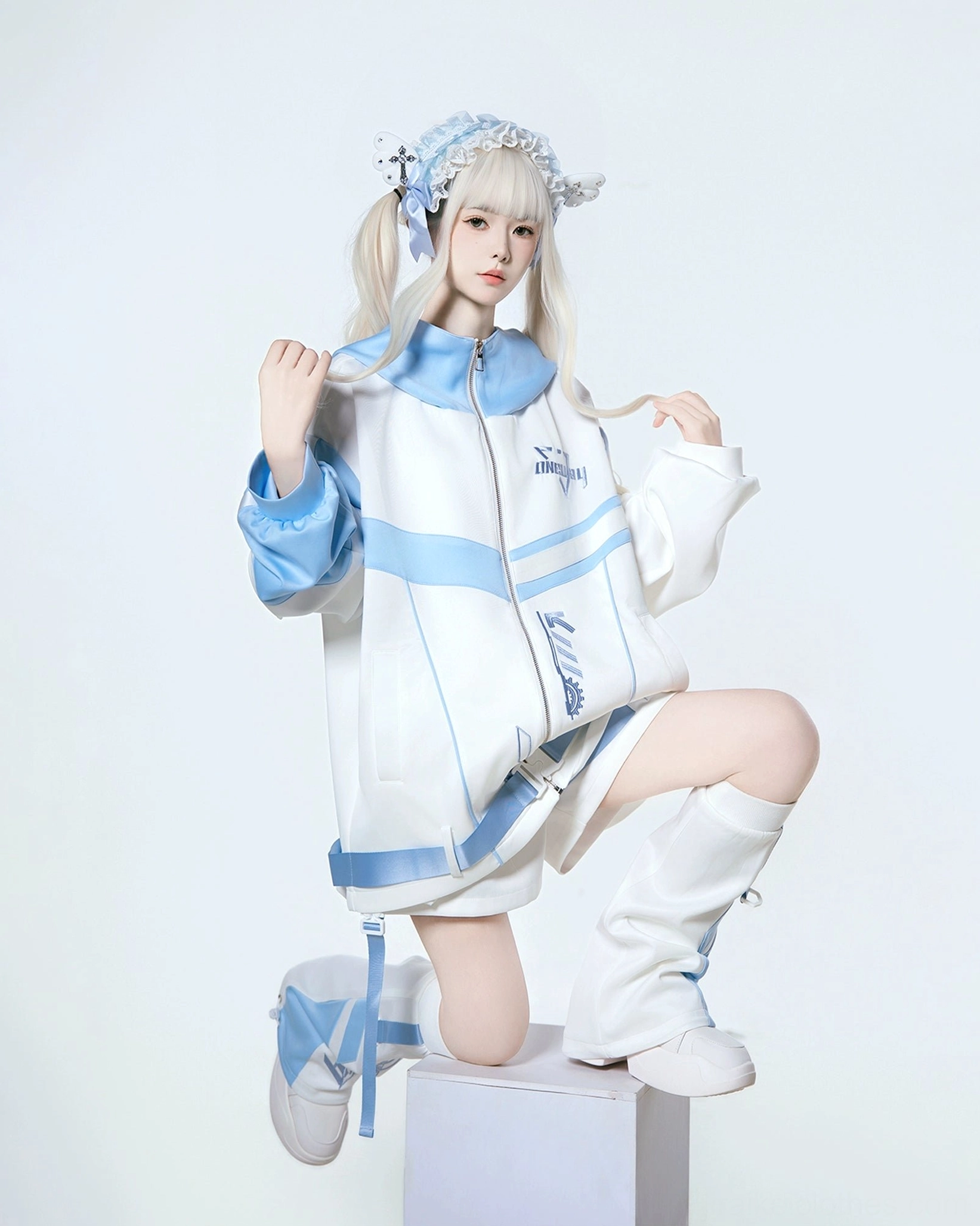 Oversized techwear hoodie set with matching leg warmers - kneeling pose on white display block showing full outfit coordination