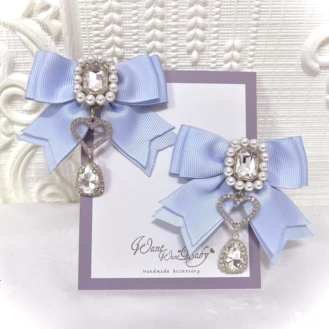 Pastel blue Jirai Kei bow hair clips carded flat lay showing rhinestone pearl center embellishment with dangling heart and crystal charm