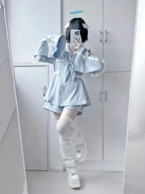 Front mirror selfie of pastel blue sailor Jirai Kei dress and shorts set with ruffled collar, front bow, and flared sleeves worn by model with short black hair in indoor wardrobe hallway