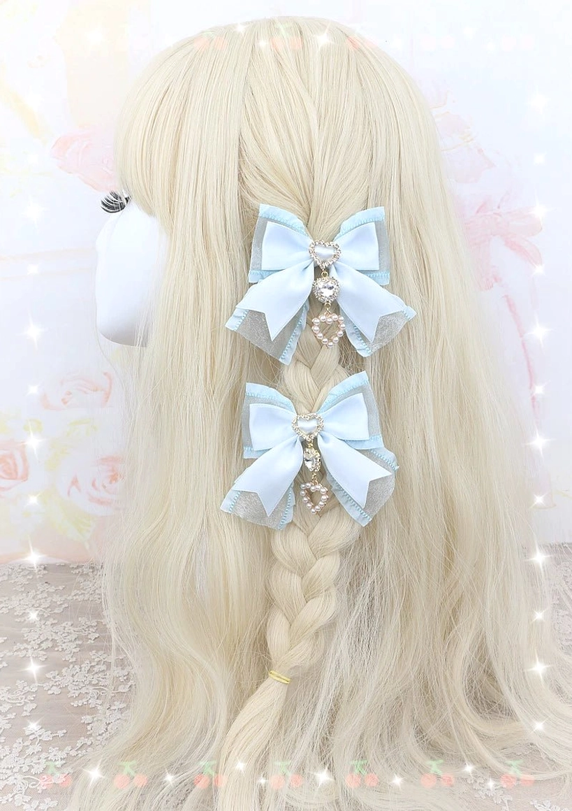 Hand-finished pearl bow hair clips showing heart-shaped rhinestone pendants and gold metal alligator clip hardware
