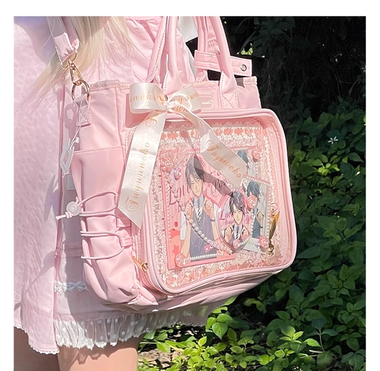 Pink anime itabag side view on human model in outdoor garden setting worn crossbody style with satin ribbon decoration and anime prints