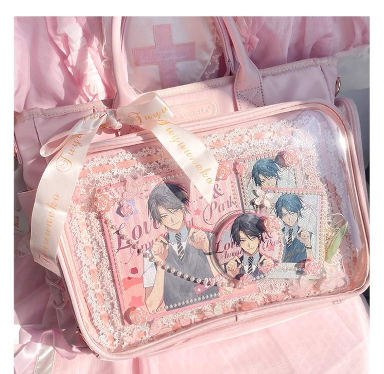 Pink anime itabag close-up top-down view showing satin ribbon bow, gold hardware, and anime character prints inside transparent display compartment