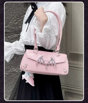 Pink bat-inspired Jirai Kei itabag with croc texture worn as shoulder bag by model in street-style outfit white blouse black skirt