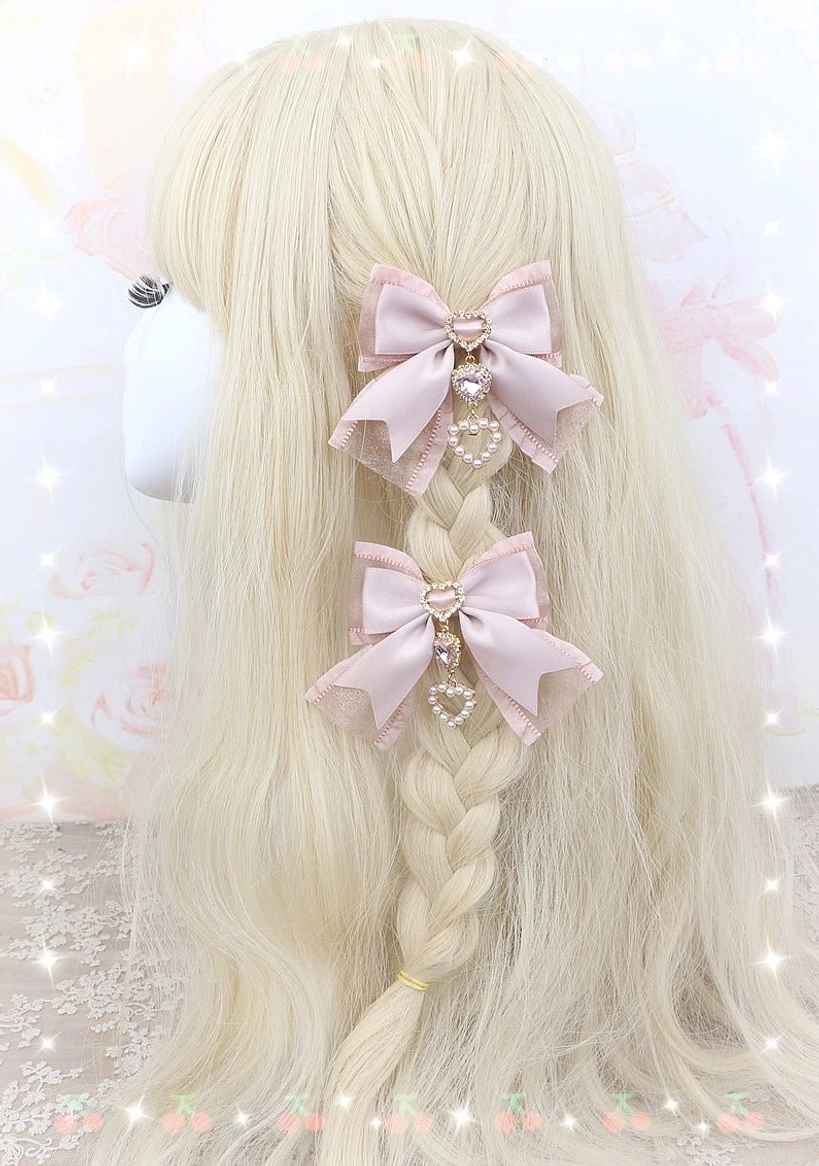 Dusty pink bows with delicate ribbon trim pair displayed on light pink twin-bun wig mannequin - front angle view
