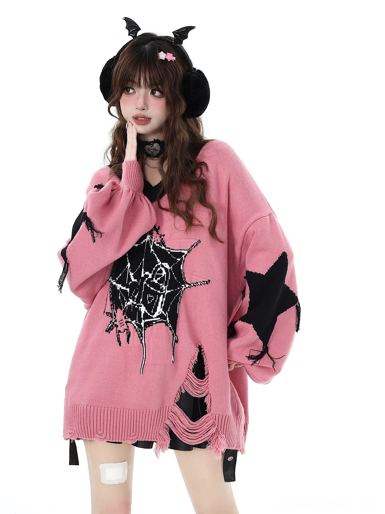 Pink Jirai Kei knit sweater with frayed side hem shown in side-front angle with model wearing devil horn earmuffs hand on cheek