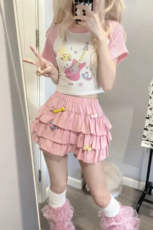 Pink Jirai Kei ruffle pumpkin shorts skirt worn with cartoon print crop top and cute pins, front mirror selfie shot showing multi-layer ruffles and high waist design
