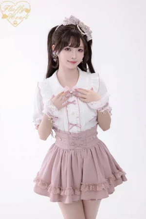 Pink Jirai Kei ruffled mini skirt with heart rhinestones and corset-style waist worn by model in studio half-body view