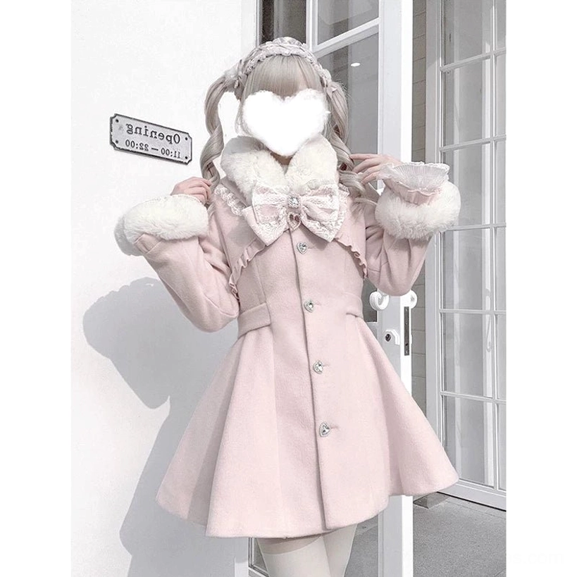 Pink Jirai Kei winter coat close-up detail shot showing large lace neck bow, removable faux fur collar trim, tailored waistline, and structured silhouette against white glass door