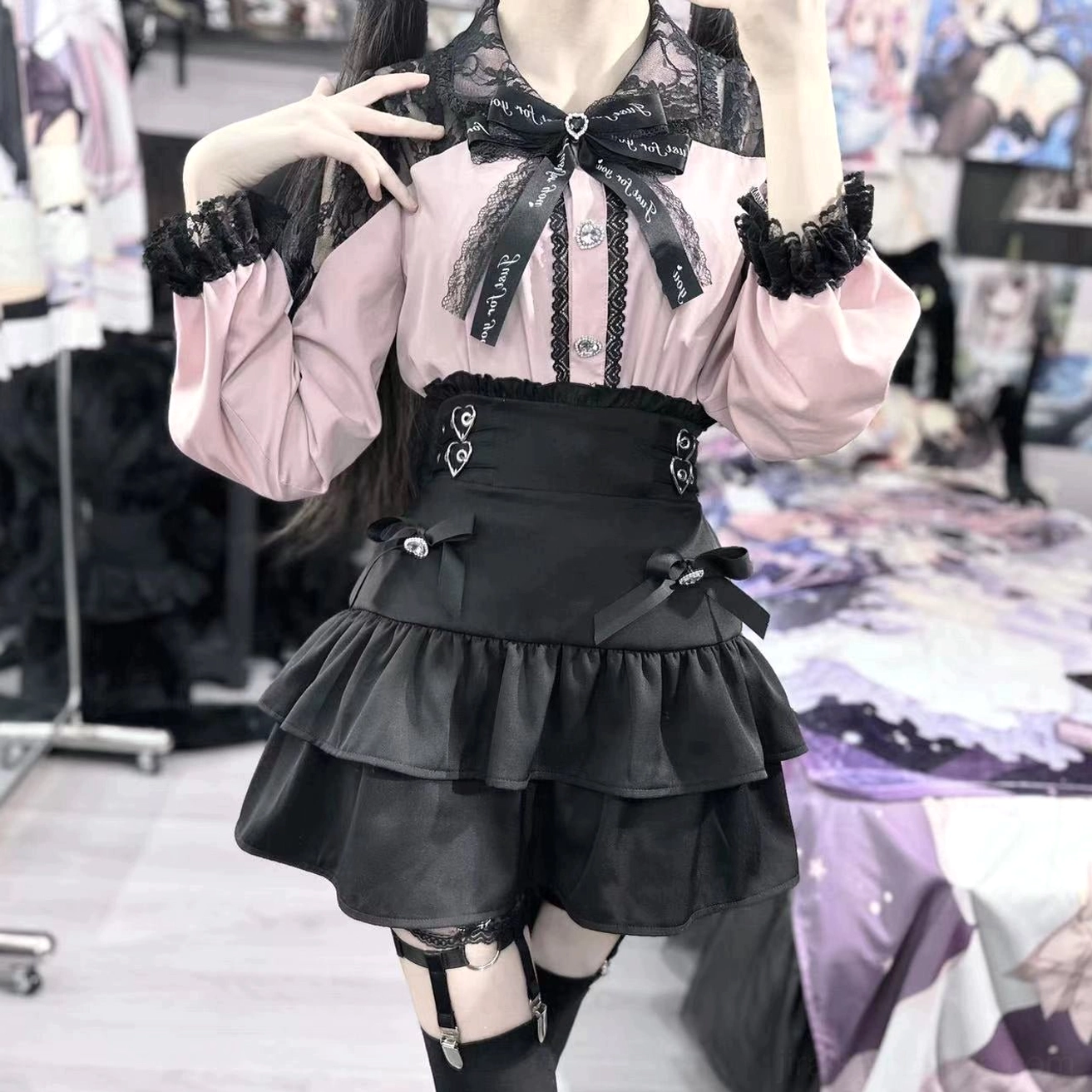 Pink Jirai Kei skirt set side-front close-up showing black bow tie decorative waist buckles and ruffled lace cuffs