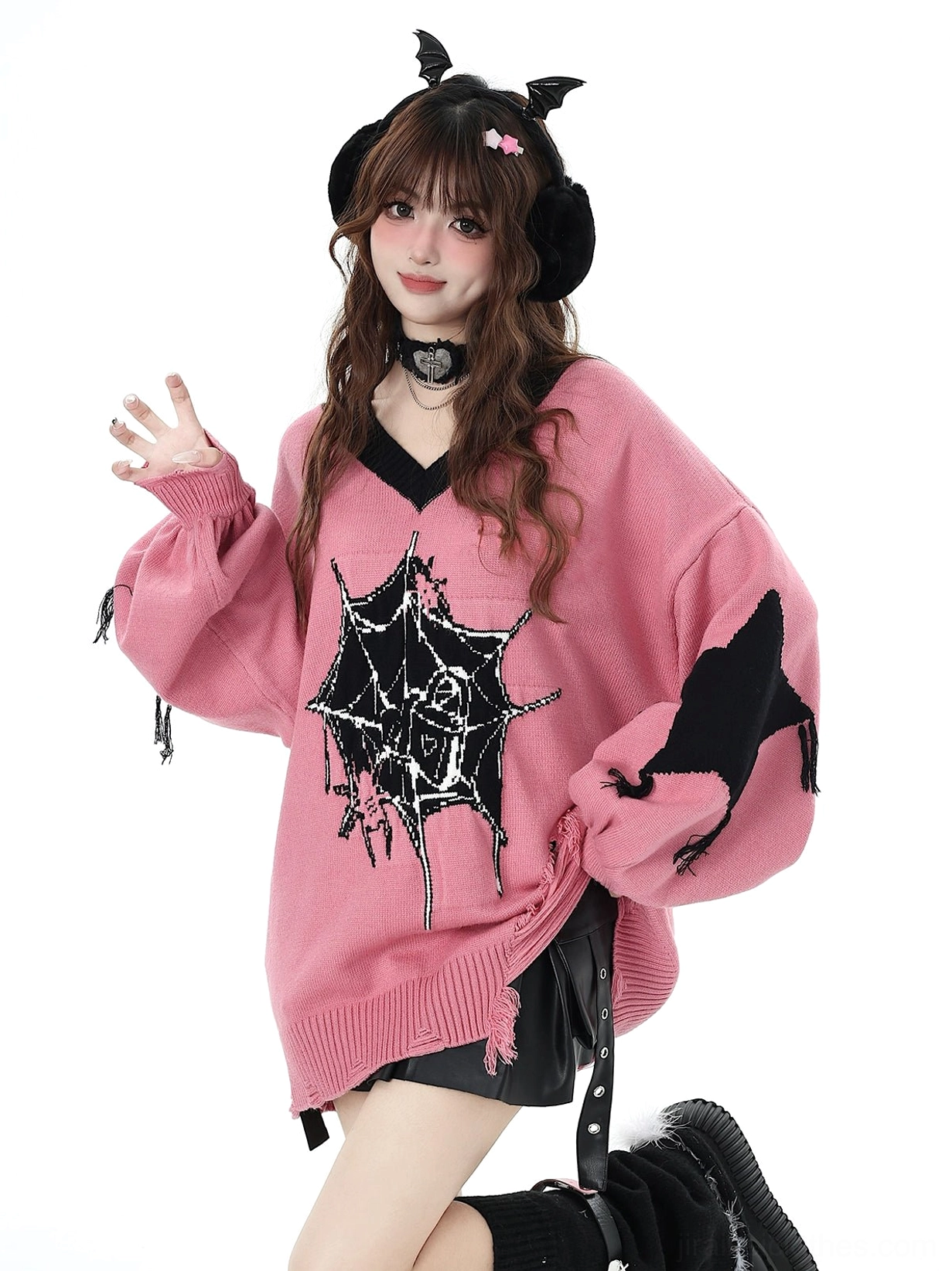 Pink V-neck Jirai Kei knit sweater with star print detail on left sleeve worn by model with devil horn earmuffs waving hand