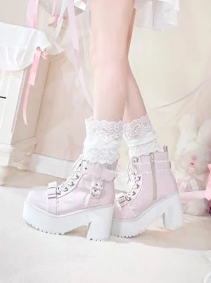 Pastel pink patent leather platform ankle boots close-up detail showing heart pearl hardware, side zipper, and lace-trimmed socks on bedroom carpet