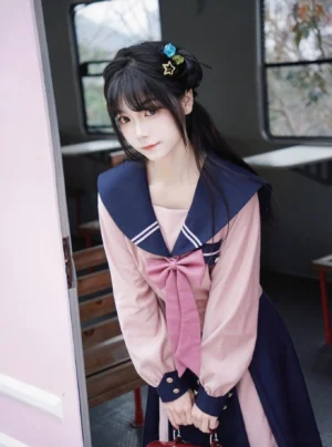 Pink sailor JK uniform long-sleeve shirt with navy trim and large pink bow tie, front full-body view worn on vintage train platform