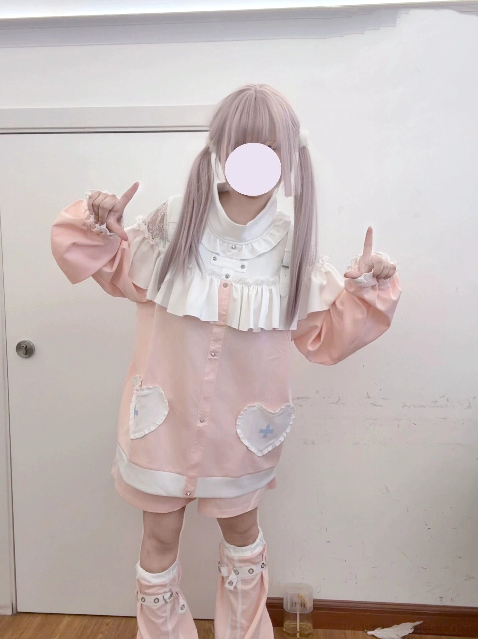 Pink sweet fashion set with ruffled collar and loose sleeves, full-body front view pose with index fingers raised, displaying heart-cross pocket details