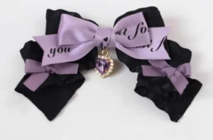 Purple and black dual-tone bow hair clip close-up with heart gem charm and decorative text detailing handcrafted Jirai style