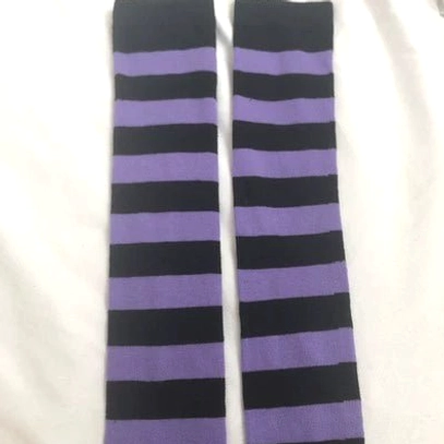 Purple and black striped over-the-knee socks flat lay, alternating horizontal stripe design, white fabric background