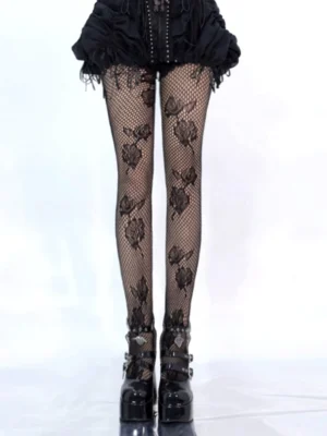 Black rose patterned fishnet pantyhose front full lower body view worn with black gothic shorts and platform heels, showing intricate mesh texture and scattered rose lace prints