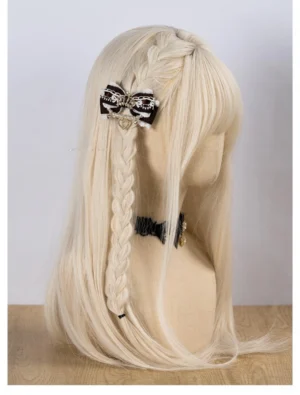 Black and white ryousangata bow hair clip worn on blonde braided mannequin head displaying crown and pearl heart pendant with lace trim from right side profile view