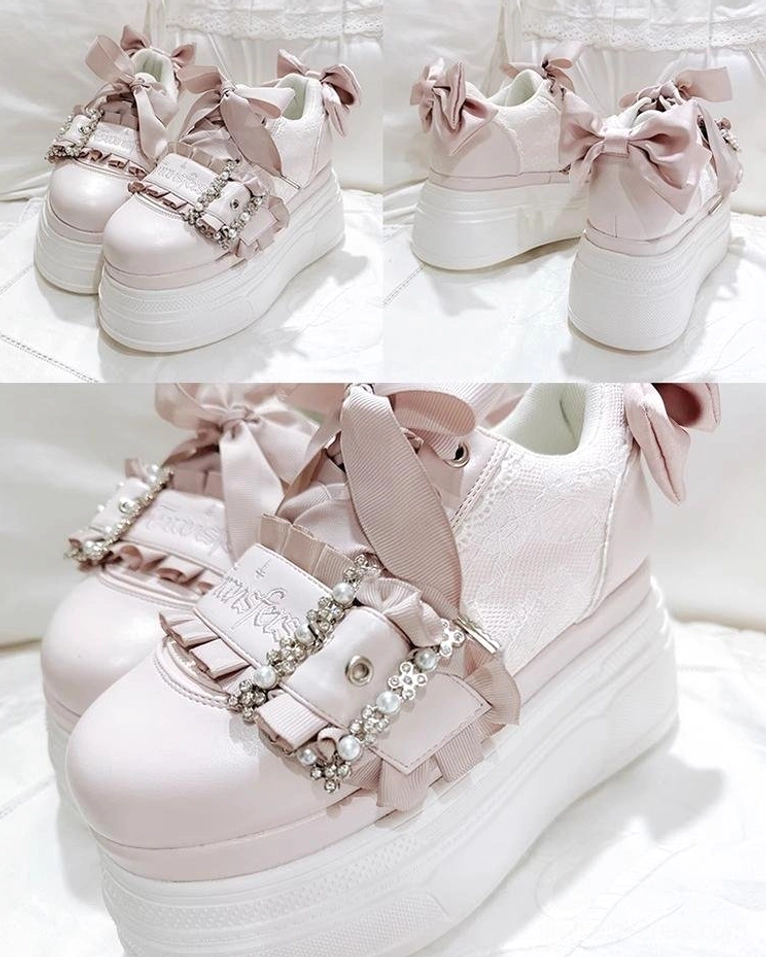 Light pink Ryousangata platform shoes close-up flat lay on white fabric surface, highlighting rhinestone buckle strap and pink satin bow decoration