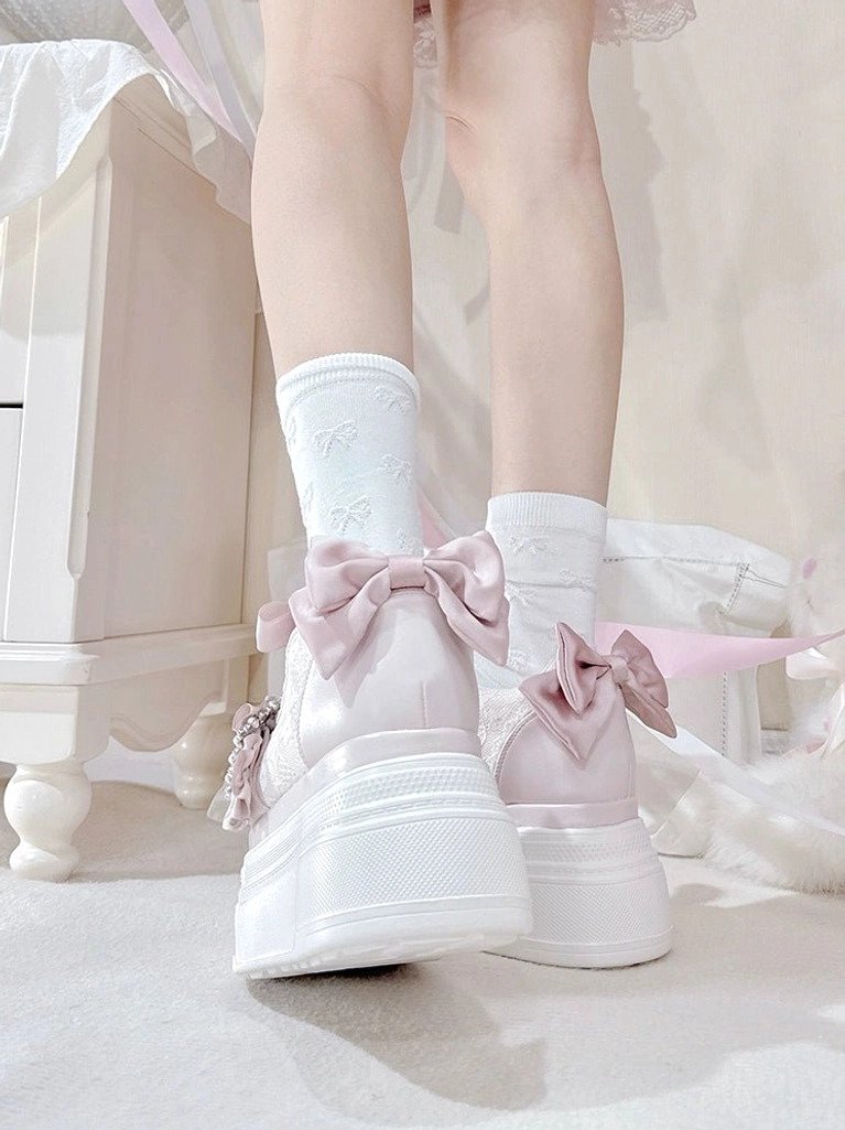 Light pink Ryousangata platform shoes side rear view on feet with white embroidered socks, displaying pink satin back bow and rhinestone buckle