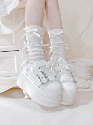 White Ryousangata platform shoes side rear view on feet with ruffled ribbon socks, displaying rhinestone strap decor and thick platform sole