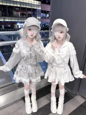 Twin models wearing gray and white ryousangata lace zip hoodies with pleated skirts, jirai kei street fashion outdoor mall setting