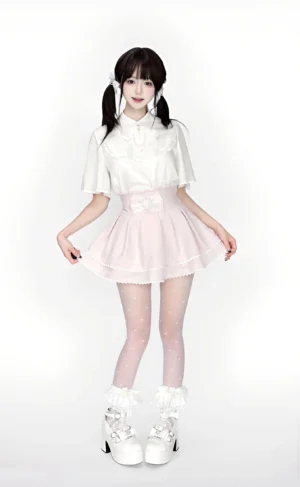 Female model in complete Ryousangata lolita set with white blouse, high-waisted pink ruffled skirt, and dotted fishnet stockings, full front-body studio shot