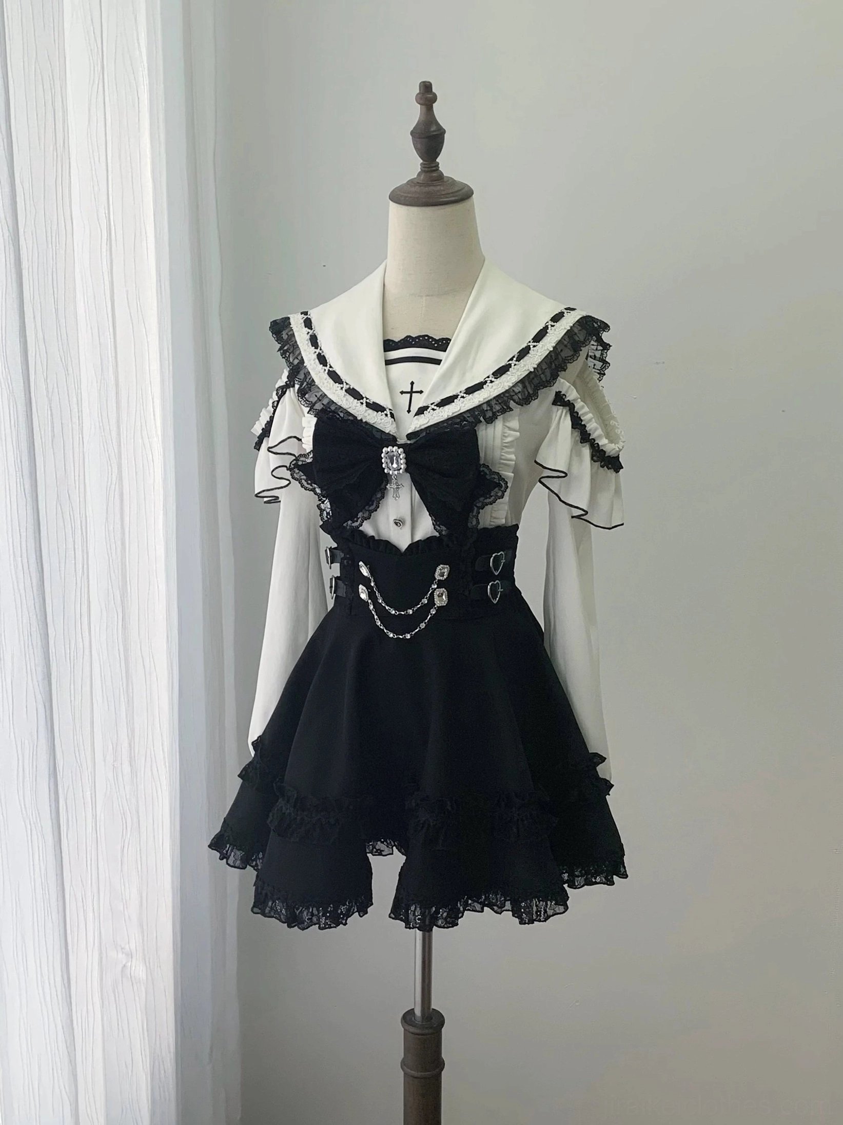 Dress form displaying sailor collar blouse with large rhinestone bow, chain waist decoration, and lace trim details, front product view