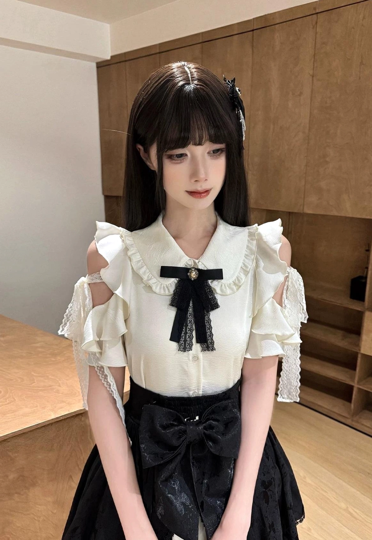Close-up front view of Seiso Kei cold-shoulder ruffled blouse with detachable black bow tie and lace cuff accents