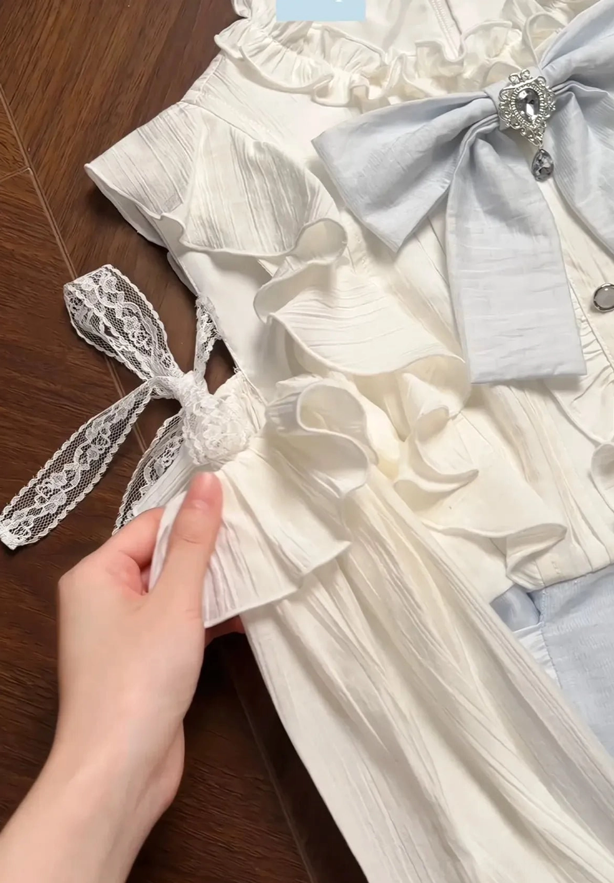 Close-up detail of Seiso Kei dress collar and strap with ruffled trim, gem-embellished bow, and lace ribbon accent