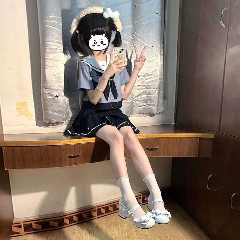 Short-sleeve puppy Jirai Kei JK uniform set frontal sitting view young girl with hair accessories mini black skirt cropped sailor top white mary jane shoes