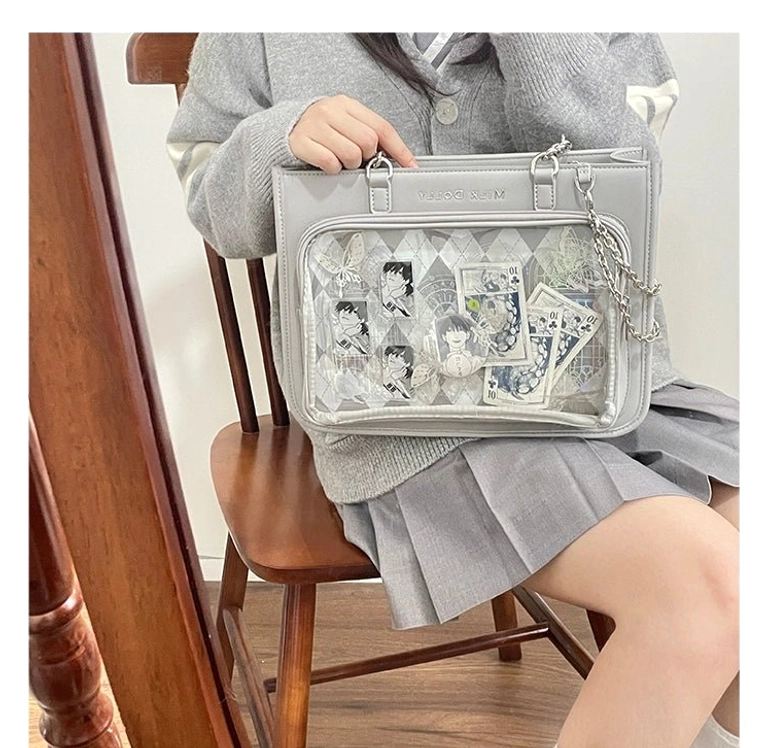 Silver checkered ita bag worn on lap with transparent display window and anime print decorations worn by girl in school uniform