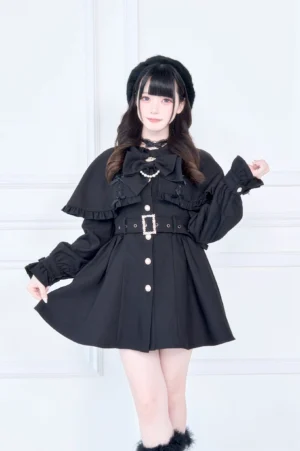 Solid black Jirai Kei cape collar trench coat with metal waist buckle and front button closure front three-quarter standing view
